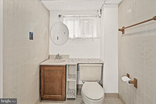 bathroom featuring toilet, vanity, tile walls, and tile patterned floors