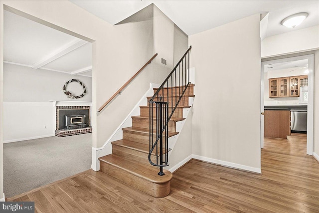 stairway with visible vents, a fireplace, baseboards, and wood finished floors