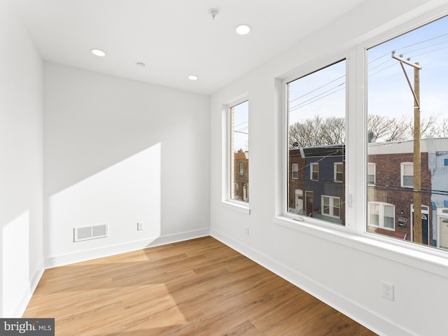 empty room with a healthy amount of sunlight and light hardwood / wood-style flooring