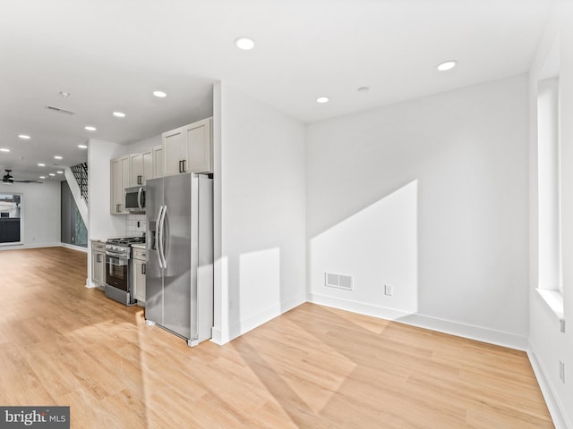 kitchen featuring gray cabinets, light hardwood / wood-style floors, ceiling fan, and appliances with stainless steel finishes