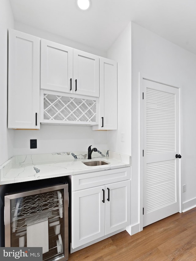 bar with white cabinets, sink, and beverage cooler