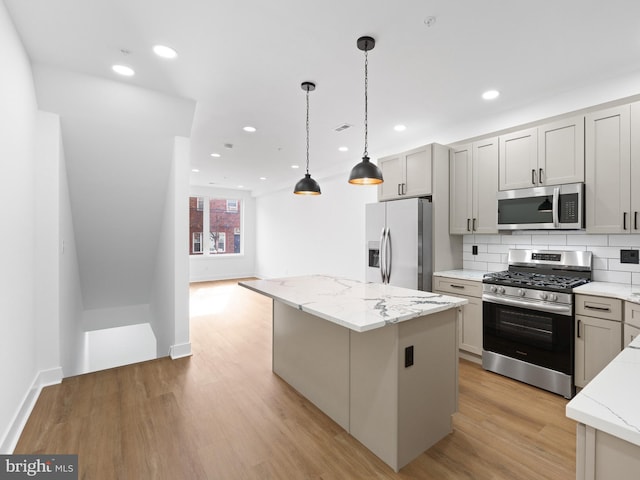 kitchen with appliances with stainless steel finishes, light stone countertops, and a kitchen island