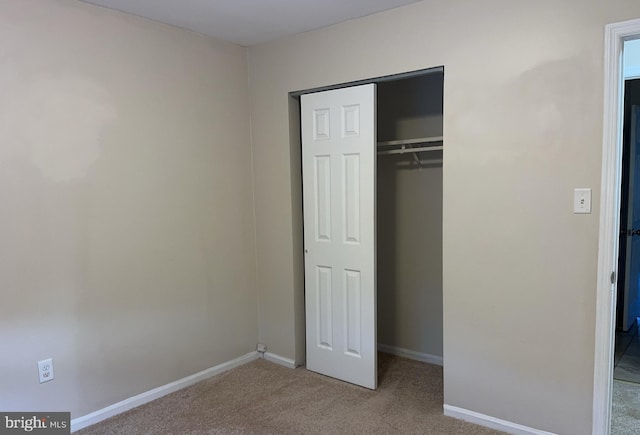 unfurnished bedroom featuring light colored carpet and a closet