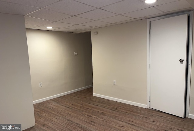 spare room featuring dark wood-type flooring and a drop ceiling