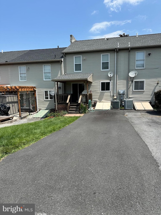 rear view of house with central AC unit and a pergola