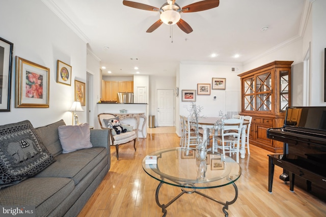 living room with crown molding, ceiling fan, and light wood-type flooring