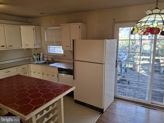 kitchen featuring hanging light fixtures, sink, white cabinets, and white refrigerator