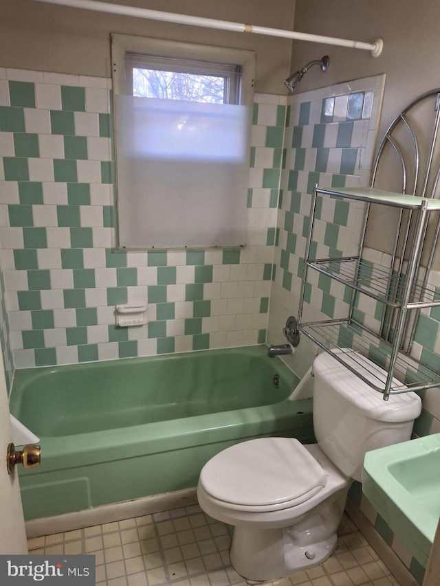 bathroom with tiled shower / bath combo, tile patterned flooring, and toilet