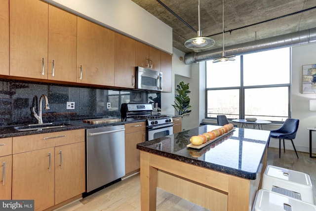 kitchen featuring pendant lighting, sink, appliances with stainless steel finishes, backsplash, and dark stone counters