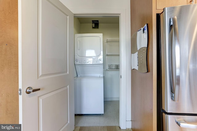 clothes washing area with light tile patterned flooring and stacked washer / dryer