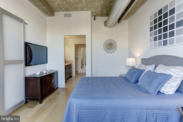 bedroom with connected bathroom and light hardwood / wood-style floors