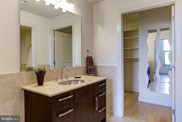 bathroom with tile walls, vanity, and wood-type flooring