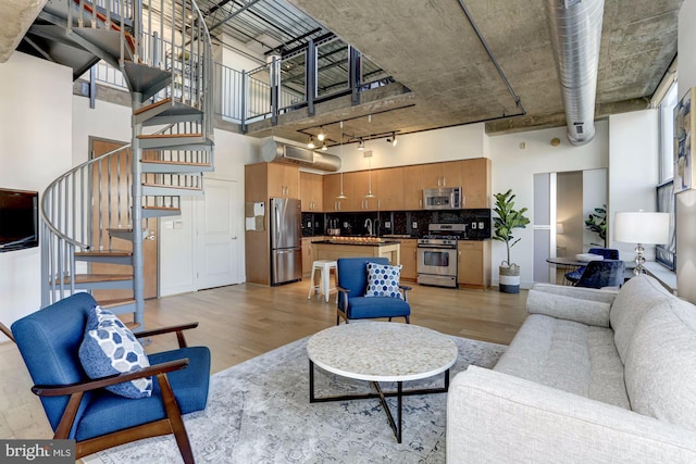 living room featuring sink, a towering ceiling, and light wood-type flooring