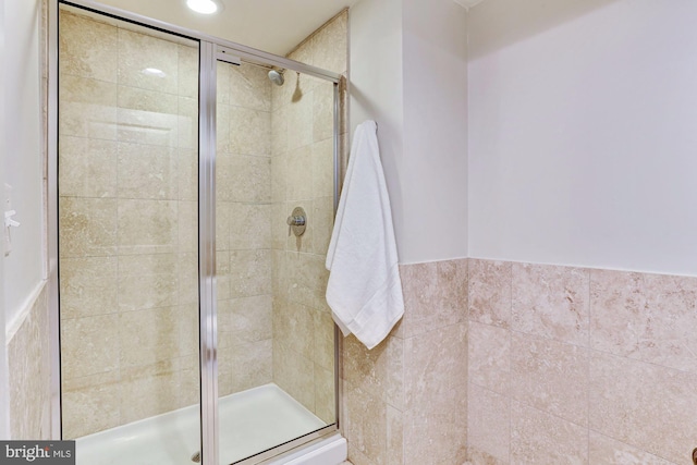 bathroom featuring tile walls and a shower with shower door