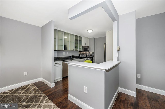 kitchen with green cabinetry, stainless steel appliances, dark hardwood / wood-style floors, and kitchen peninsula