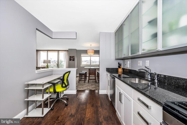 kitchen with pendant lighting, sink, dark stone countertops, stainless steel appliances, and dark hardwood / wood-style flooring