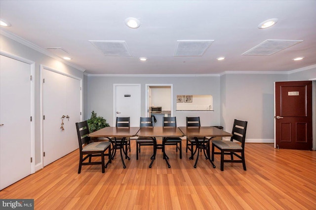 dining room with crown molding and light hardwood / wood-style floors