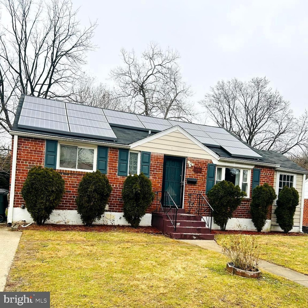 ranch-style home featuring a front lawn and solar panels