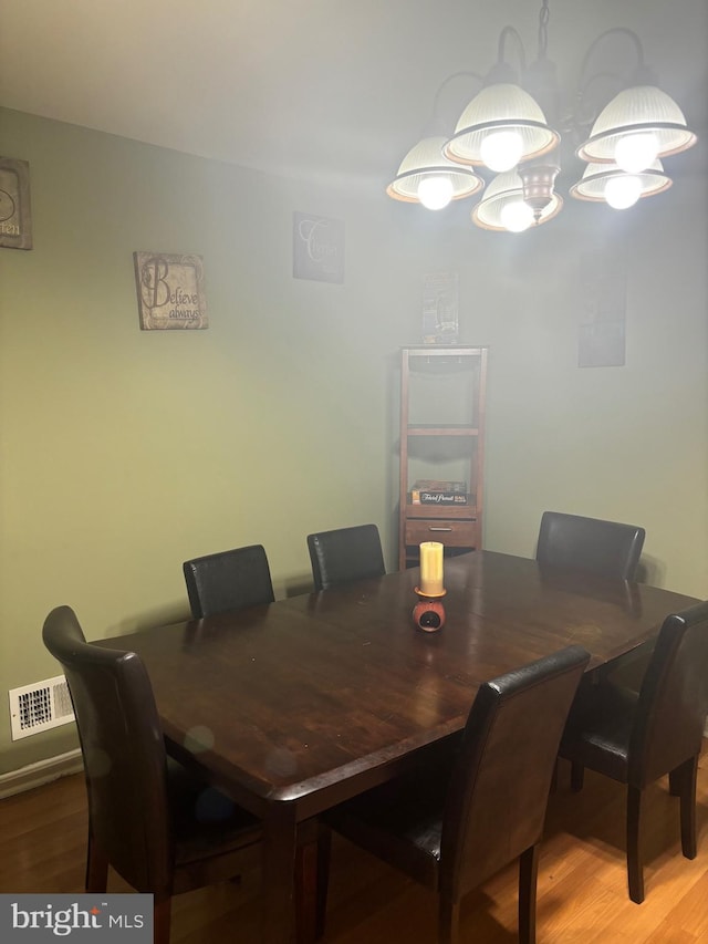 dining space with wood-type flooring and a chandelier