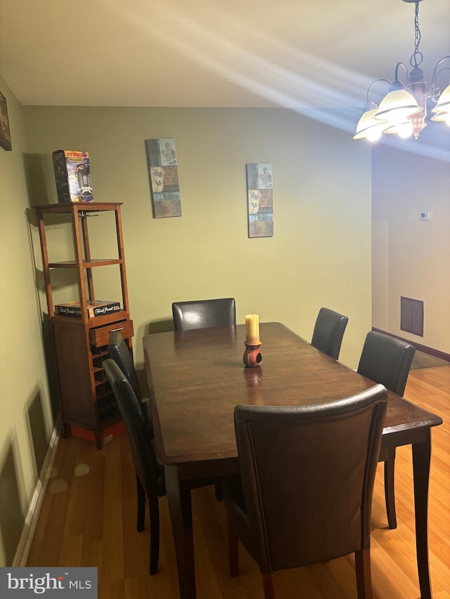 dining room with wood-type flooring and a notable chandelier