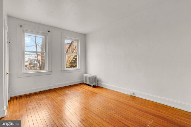 empty room with radiator heating unit and light hardwood / wood-style flooring