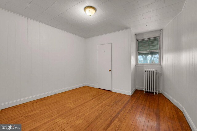 unfurnished room featuring radiator and hardwood / wood-style floors