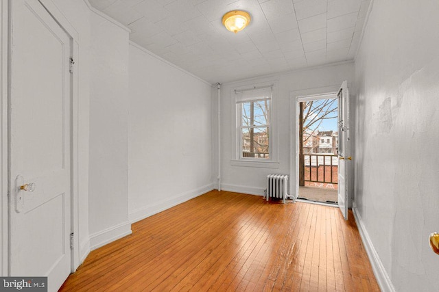 unfurnished room with crown molding, radiator, and light wood-type flooring