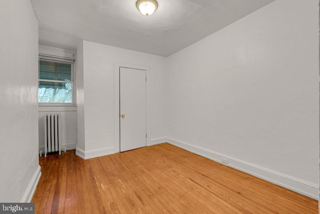 empty room featuring wood-type flooring and radiator