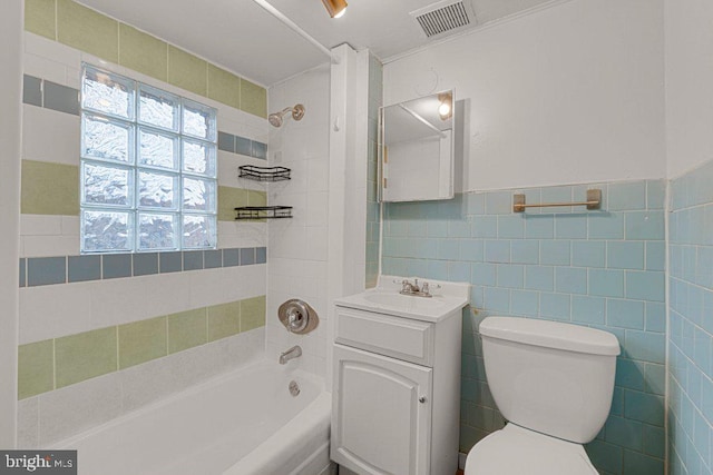 full bathroom with tile walls, vanity, toilet, and tiled shower / bath