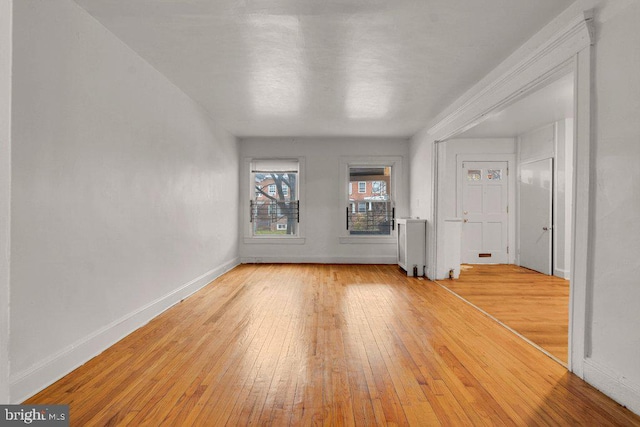 unfurnished living room with radiator heating unit and light wood-type flooring