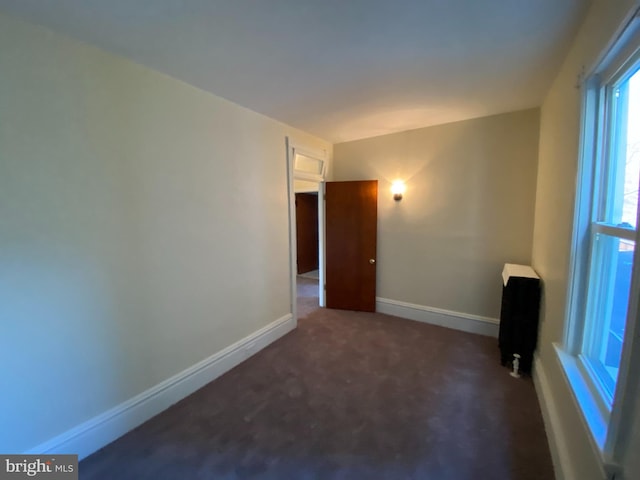 empty room with radiator and dark carpet