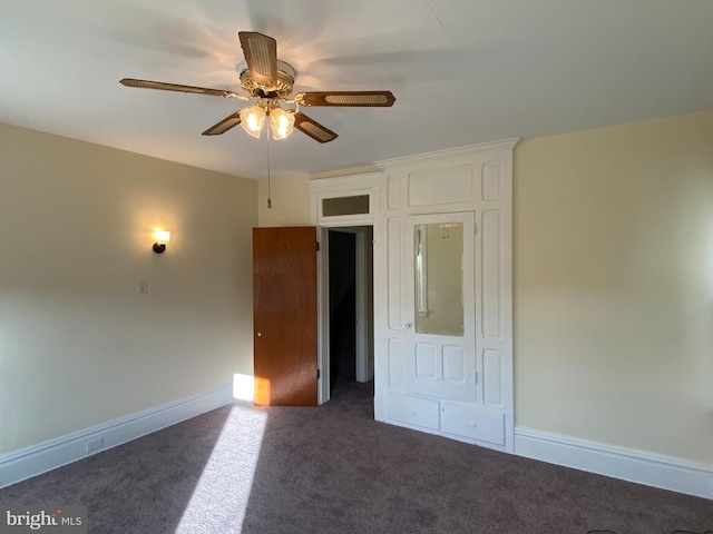 unfurnished bedroom with ceiling fan and dark carpet