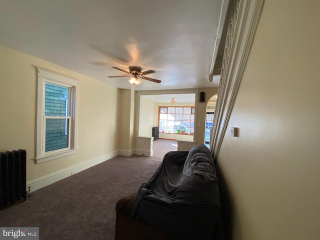 carpeted living room with radiator heating unit and ceiling fan