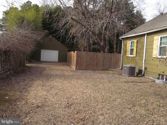 view of yard featuring cooling unit, a garage, and an outbuilding