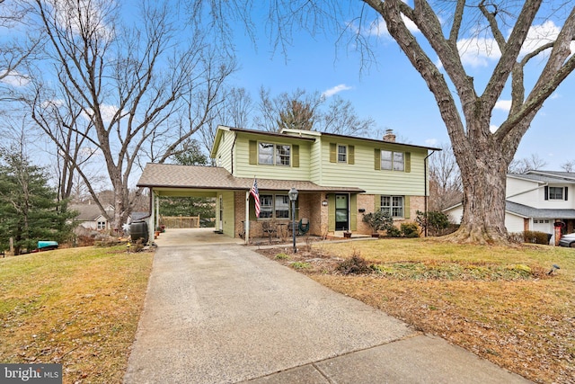 traditional home featuring concrete driveway, a front lawn, a chimney, and brick siding