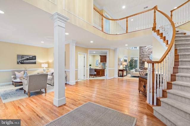 foyer featuring crown molding, hardwood / wood-style flooring, a high ceiling, and ornate columns