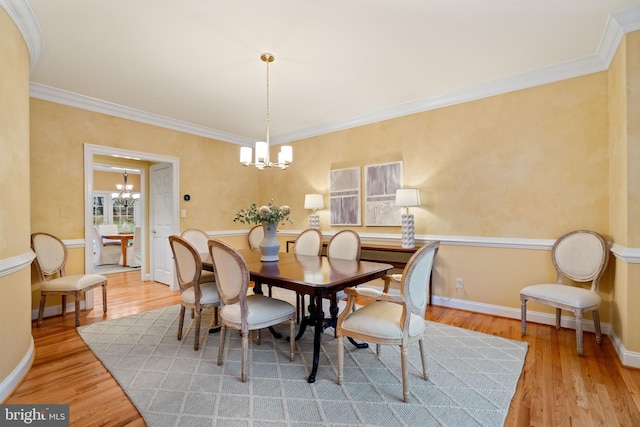 dining area featuring crown molding, light hardwood / wood-style floors, and a chandelier