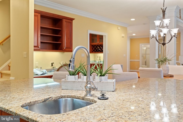 kitchen featuring sink, hanging light fixtures, a notable chandelier, crown molding, and light stone countertops