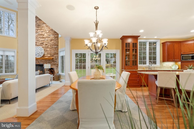 dining room featuring decorative columns, sink, a fireplace, and light hardwood / wood-style flooring