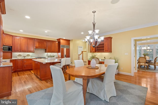 dining area featuring crown molding, a chandelier, and light hardwood / wood-style floors