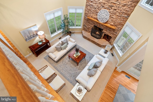 living room featuring hardwood / wood-style flooring, a stone fireplace, and a high ceiling