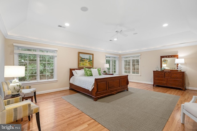 bedroom featuring a raised ceiling, ornamental molding, ceiling fan, and light wood-type flooring