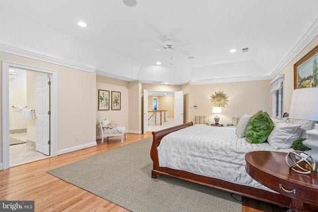 bedroom featuring ensuite bath, ornamental molding, a tray ceiling, and light hardwood / wood-style flooring