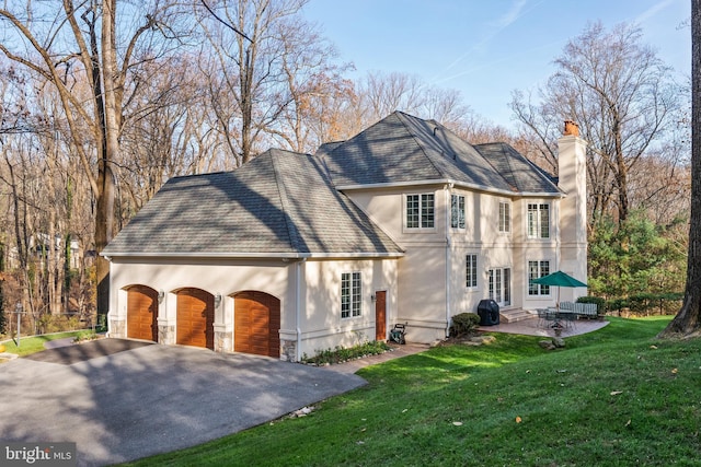 view of front of house featuring a garage, a patio area, and a front yard