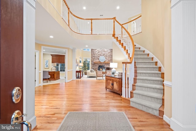 entrance foyer with a fireplace, a towering ceiling, and light hardwood / wood-style flooring