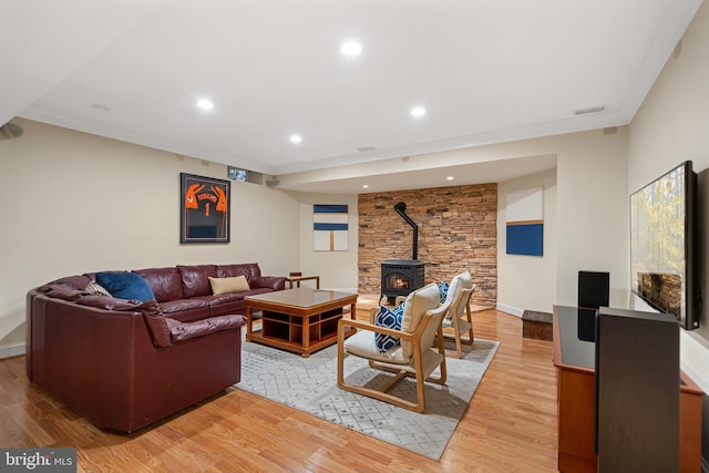 living room with crown molding, wood-type flooring, and a wood stove