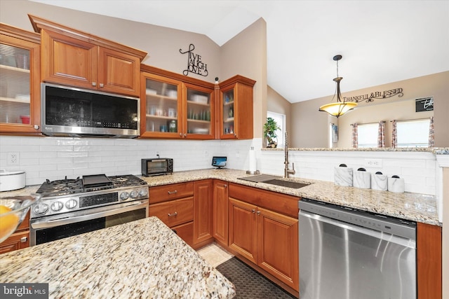 kitchen featuring pendant lighting, appliances with stainless steel finishes, sink, and light stone counters