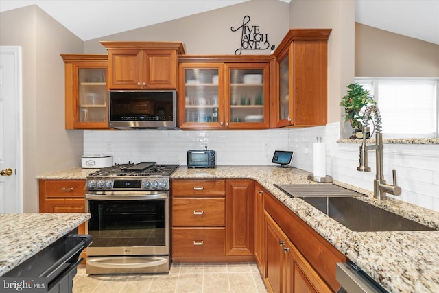 kitchen with sink, appliances with stainless steel finishes, tasteful backsplash, light stone countertops, and vaulted ceiling