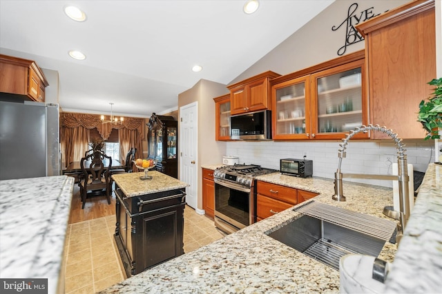 kitchen with vaulted ceiling, a kitchen island, appliances with stainless steel finishes, sink, and light stone countertops