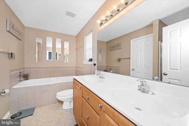 bathroom featuring vanity, a relaxing tiled tub, and toilet